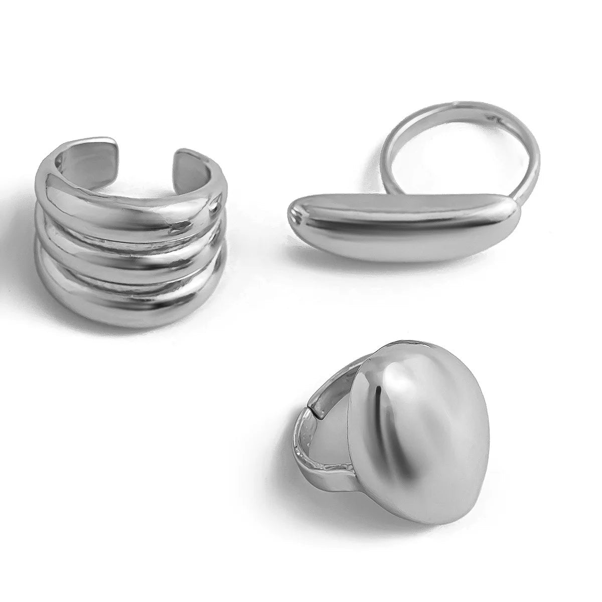 Three silver adjustable rings: multi-band stacked ring, elongated bar ring, and large oval dome statement ring.