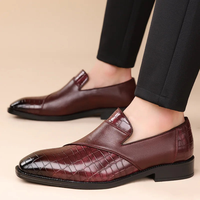 Men's burgundy leather slip-on loafers with crocodile-embossed pattern, worn with black dress trousers, low heel