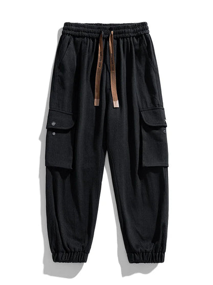 Black cargo jogger pants with elastic waistband, drawstring, multiple snap-button pockets, and tapered ankle cuffs for men.