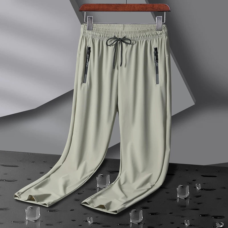 Men's light green stretch sweatpants with zippered pockets and drawstring waist on hanger display