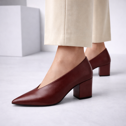 Women's burgundy Italian leather block heel pumps with pointed toe and V-cut vamp, paired with cream trousers.