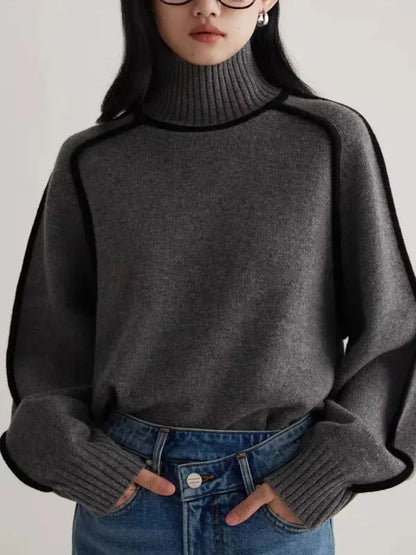 Gray turtleneck knit sweater with black contrast piping trim, long sleeves, worn with blue jeans