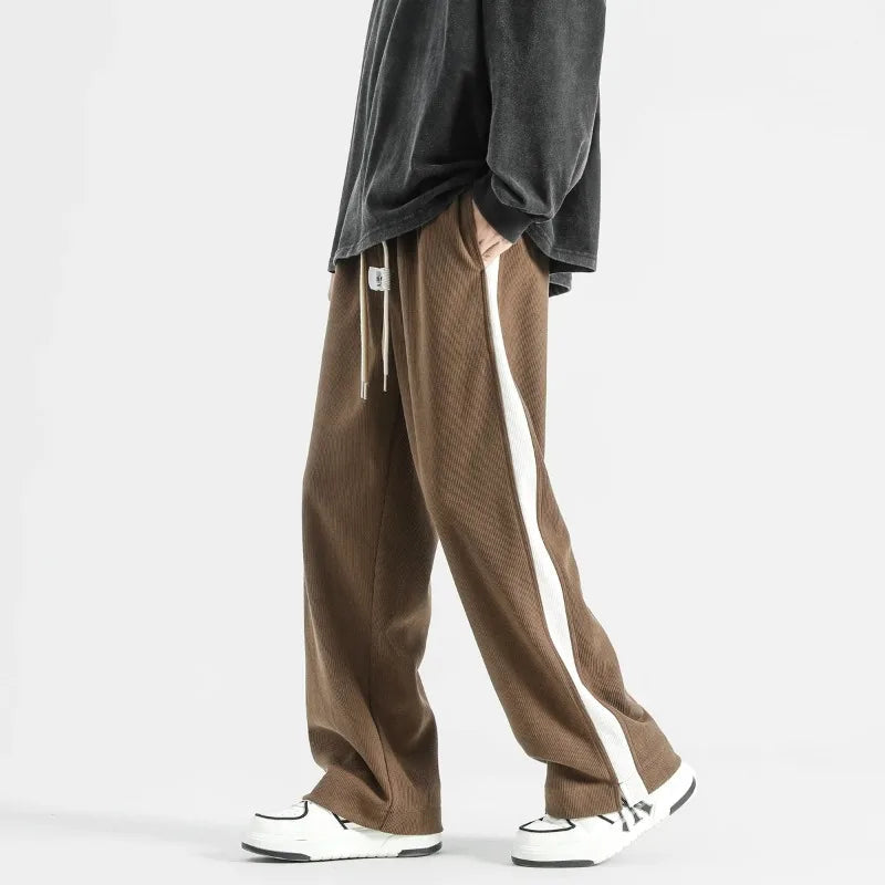 Brown wide-leg corduroy drawstring joggers with white side stripe, paired with gray oversized top and white sneakers