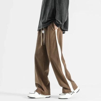 Brown wide-leg corduroy drawstring joggers with white side stripe, paired with gray oversized top and white sneakers