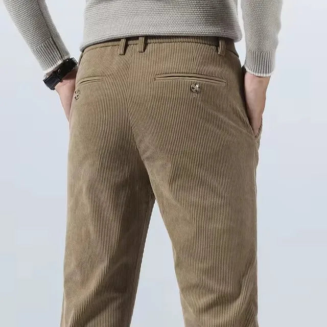 Man wearing khaki corduroy slim fit chino pants from behind, showing back pocket detail and straight leg silhouette.