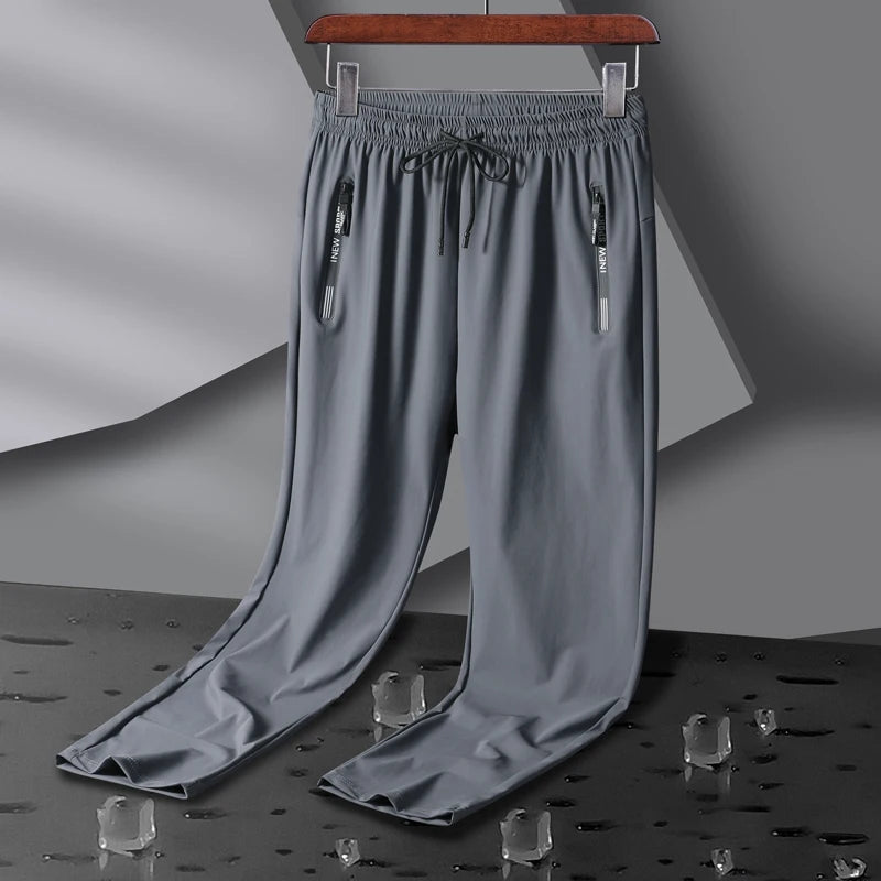 Gray men's stretch sweatpants with elastic drawstring waist, dual zip pockets, and relaxed straight-leg fit on hanger.