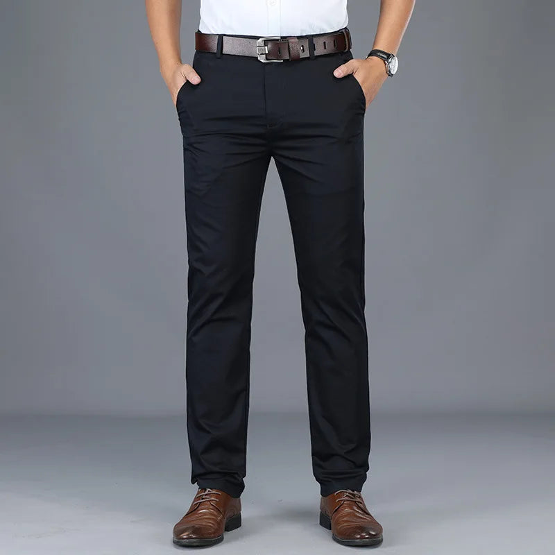 Man wearing slim fit navy blue cotton dress pants with brown leather belt and oxford shoes, front view
