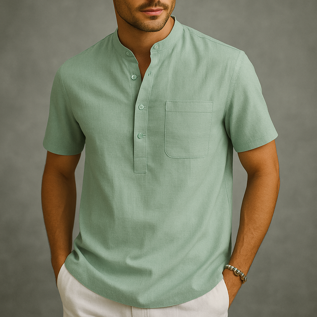 Man wearing a sage green linen short-sleeve henley shirt with band collar, chest pocket, and partial button placket.
