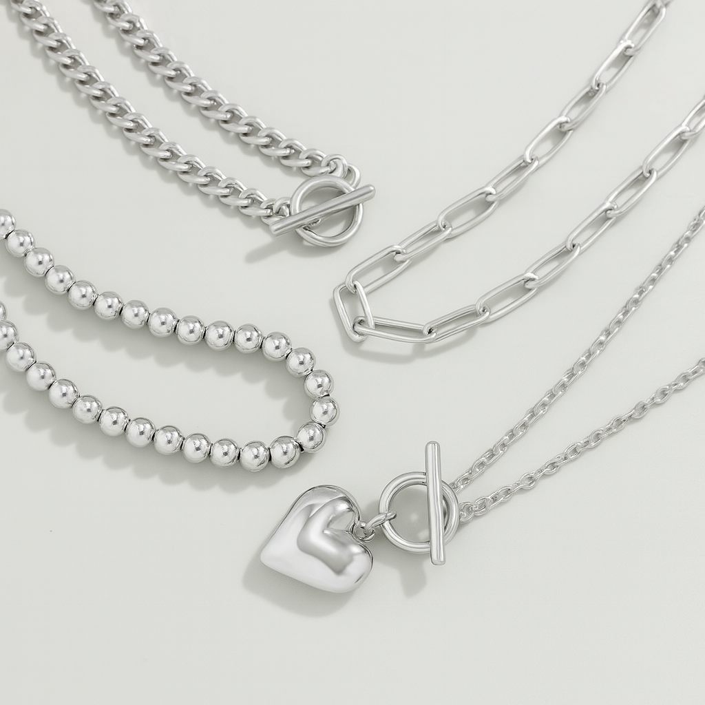 Silver layered necklace set featuring curb chain, bead chain, paperclip chain, and heart pendant with toggle clasps