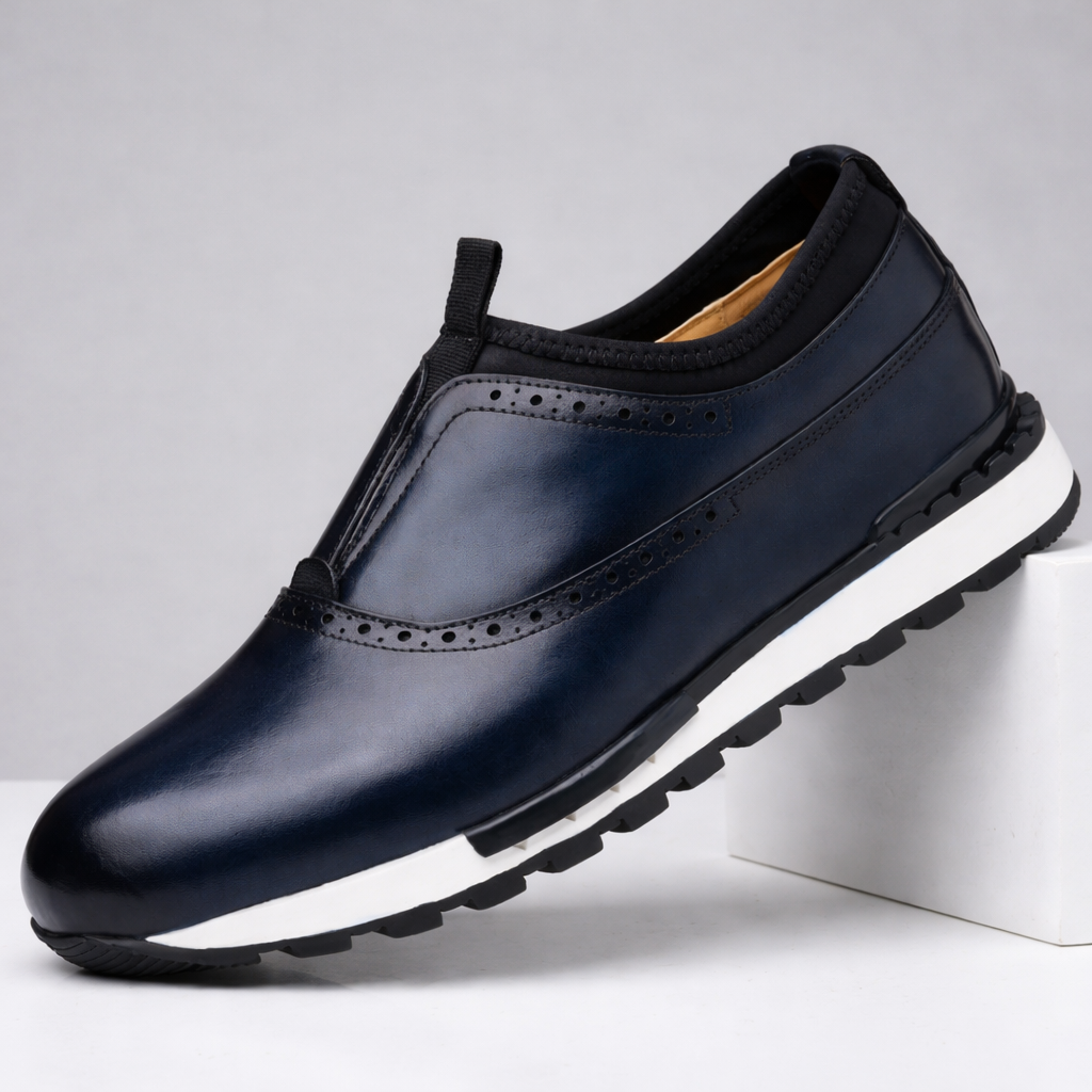Navy blue leather men's slip-on loafer with brogue perforations, black collar, and white rubber sole on white platform.