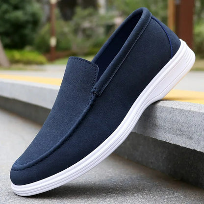Navy blue suede slip-on loafers for men with white rubber sole, displayed on concrete steps outdoors