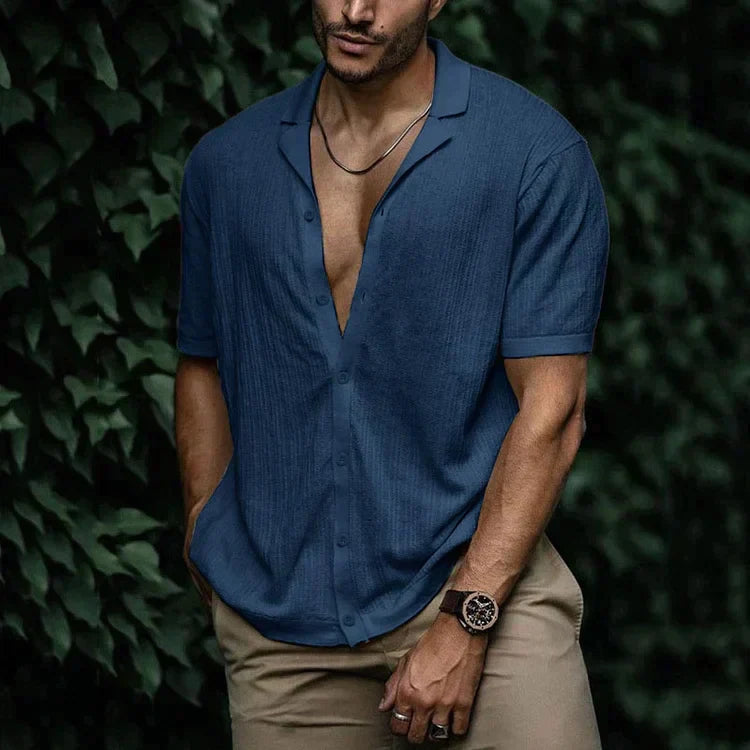 Man wearing navy blue short sleeve button-down linen shirt with chest pocket, paired with khaki pants and watch.