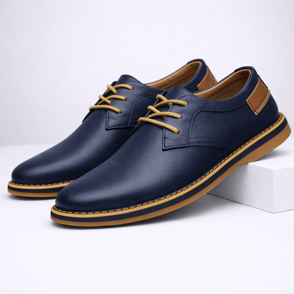 Navy blue men's leather lace-up dress shoes with tan sole, gold laces, and suede heel patch on white background