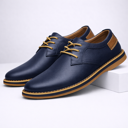 Navy blue men's leather lace-up dress shoes with tan sole, gold laces, and suede heel patch on white background