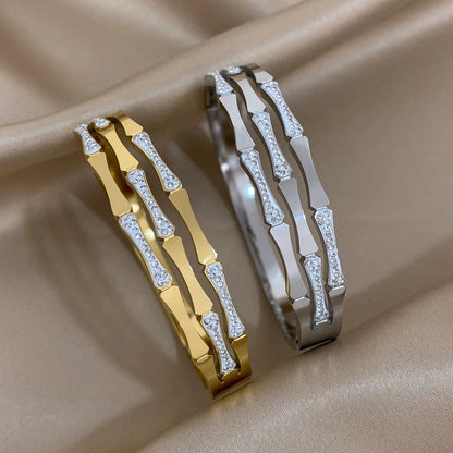 Gold and silver geometric bangle bracelets with crystal stone accents displayed on beige satin fabric