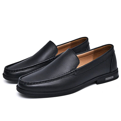 Black men's leather slip-on loafers with contrast stitching, tan interior lining, and low heel on white background
