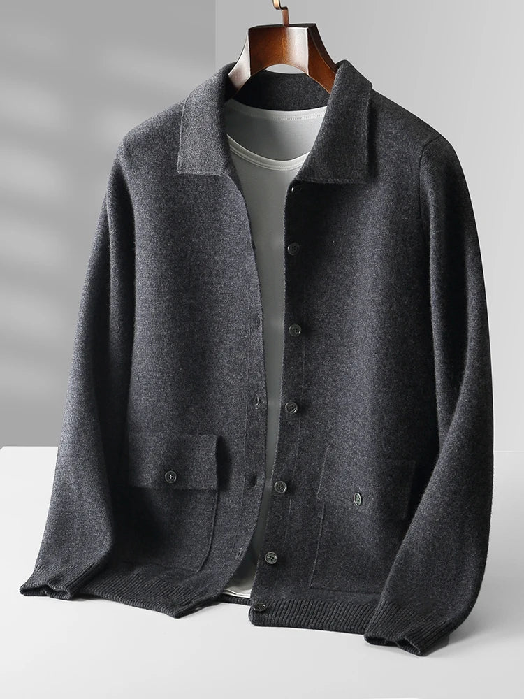 Dark gray merino wool men's button-up cardigan jacket with collar, front pockets, and ribbed hem on wooden hanger