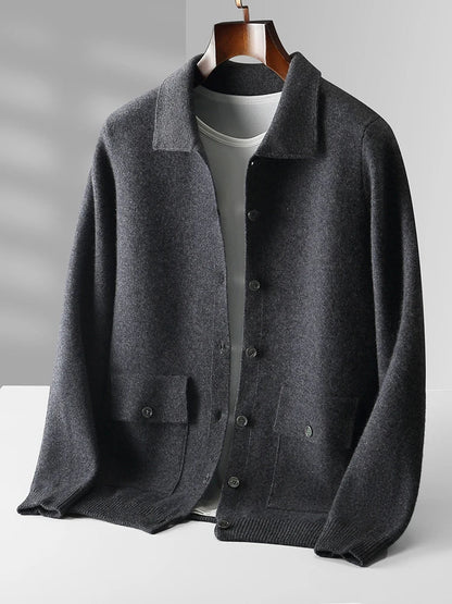 Dark gray merino wool men's button-up cardigan jacket with collar, front pockets, and ribbed hem on wooden hanger