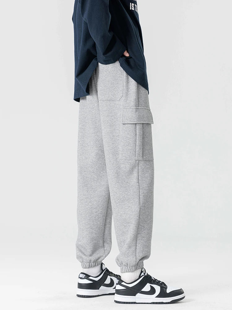 Men's gray cargo joggers with side pockets and elastic cuffs worn with black and white sneakers