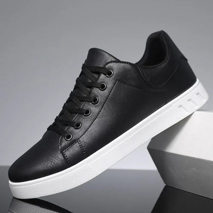 Black leather lace-up low-top men's sneakers with white sole, displayed on geometric white blocks against gray background