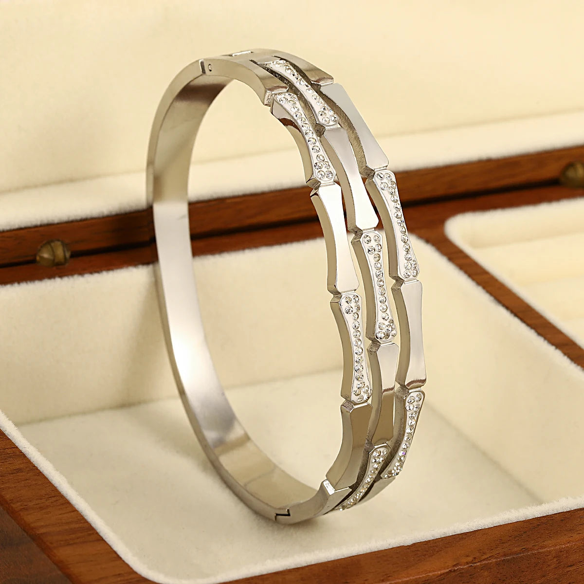Silver tone bangle bracelet with geometric links and sparkling crystal stone accents displayed in jewelry box