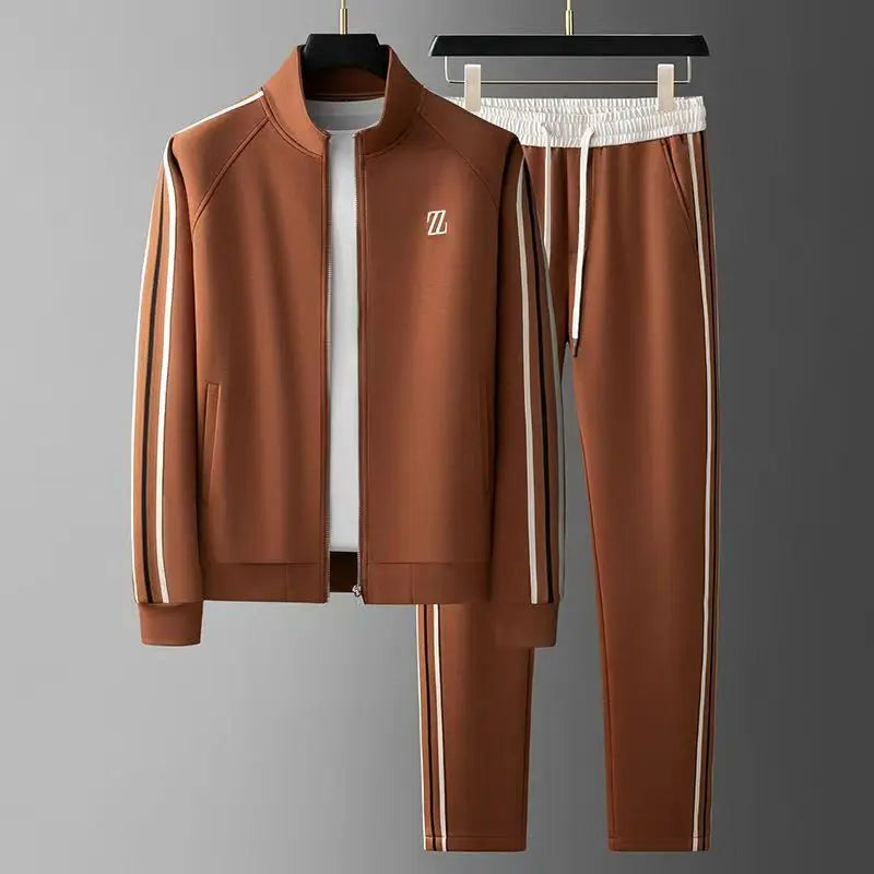Brown men's zip-up tracksuit set with white and gold side stripes, stand collar jacket and matching jogger pants on hangers