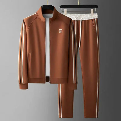 Brown men's zip-up tracksuit set with white and gold side stripes, stand collar jacket and matching jogger pants on hangers