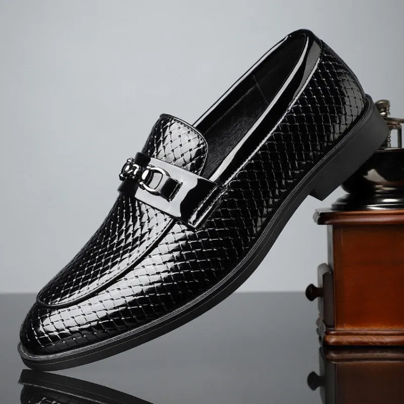 Black men's leather slip-on loafers with woven texture pattern and silver metal horsebit buckle detail on reflective surface