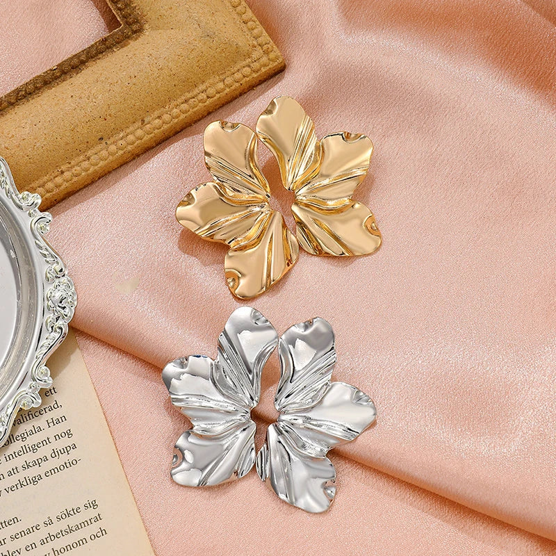 Gold and silver tone large ruffled flower statement earrings displayed on pink satin fabric with mirror accent