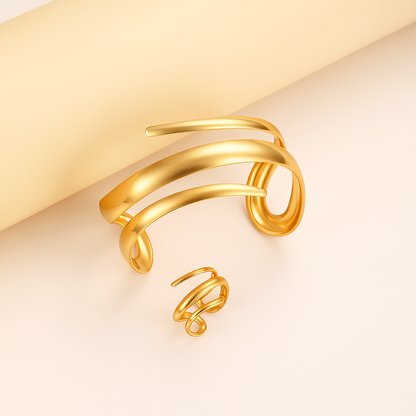 Gold-tone spiral wrap cuff bracelet and matching ring set with sleek multi-band design on neutral background