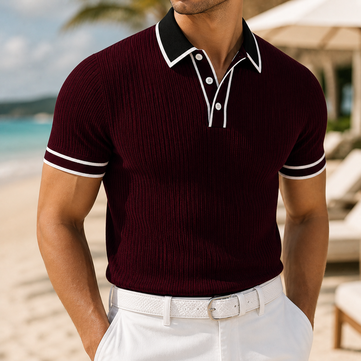 Men's burgundy ribbed knit polo shirt with black collar, white contrast trim, short sleeves, worn with white trousers on beach.