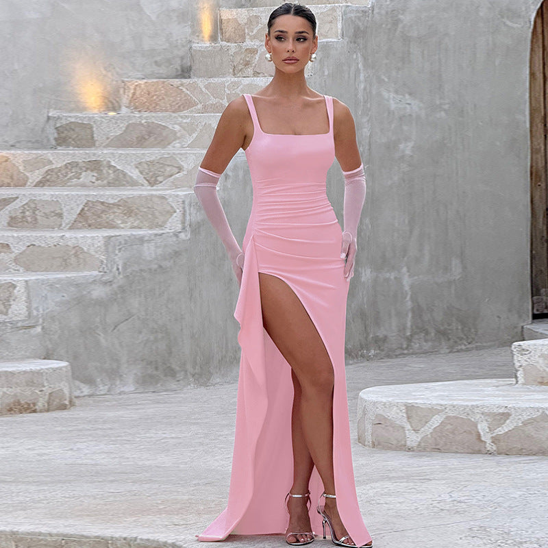 Woman wearing pink square neck high slit maxi dress with sheer gloves and silver heels, standing on stone steps.