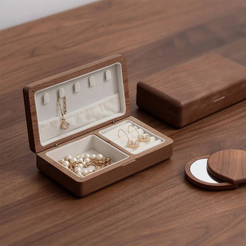 Wooden jewelry box organizer with velvet interior compartments for earrings, necklaces, and rings on walnut wood surface