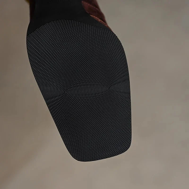 Bottom view of black rubber sole with circular tread pattern on women's square toe leather block heel pumps