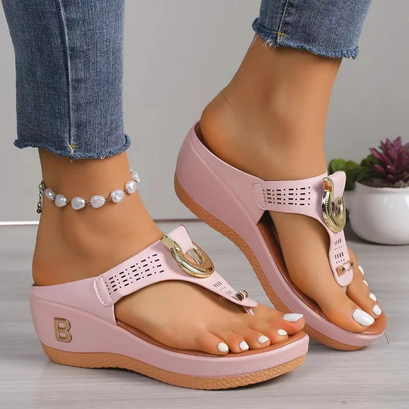 Pink wedge flip-flop sandals with gold buckle detail, platform sole, and pearl anklet accessory on female model.