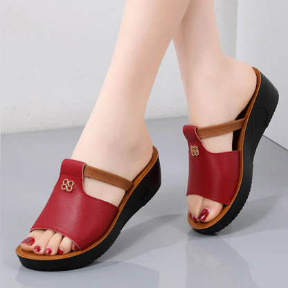 Red women's platform slide sandals with cutout detail, tan accent strap, gold embellishment, and black wedge sole.