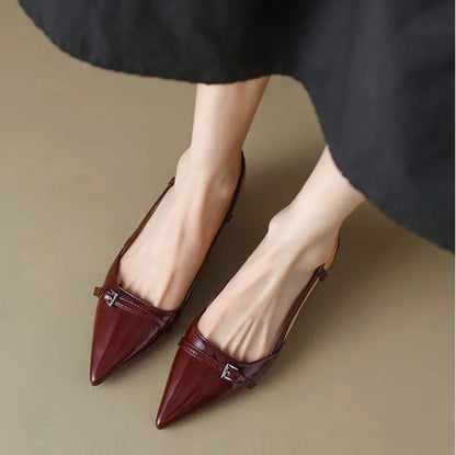 Burgundy patent leather pointed-toe slingback pumps with buckle strap detail on block heels, worn with black midi skirt