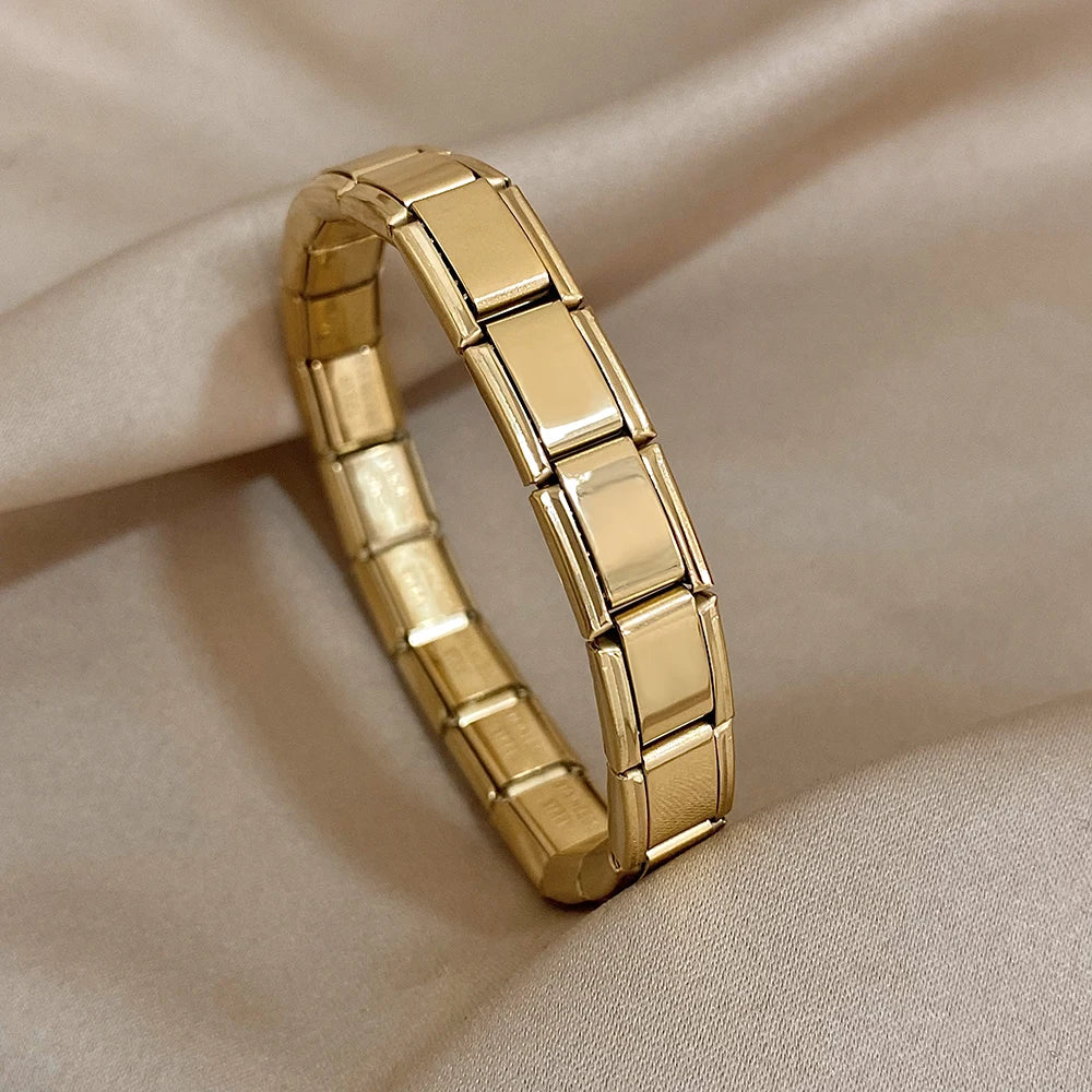 Gold interlocking link chain bracelet for women with polished rectangular segments on beige fabric background