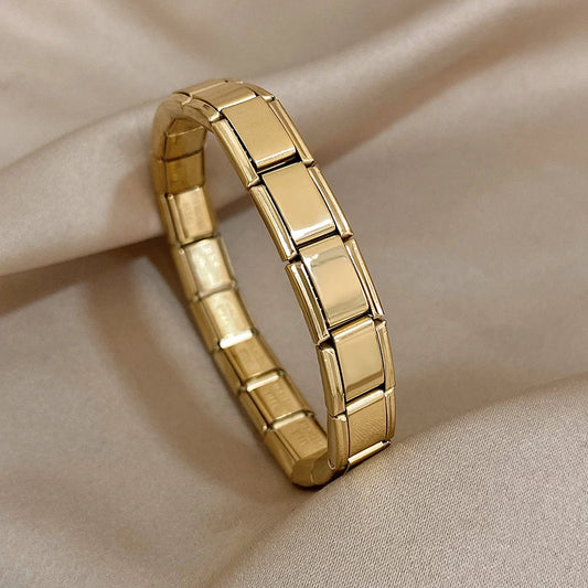 Gold interlocking link chain bracelet for women with polished rectangular segments on beige fabric background