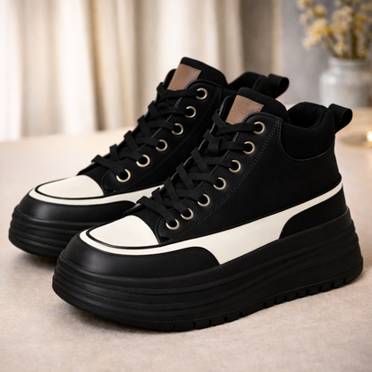 Black and white women's high-top platform sneakers with chunky sole, lace-up closure, and metallic eyelets.