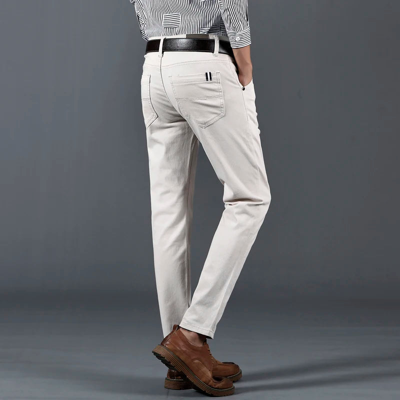 Men's slim-fit white cotton dress pants with black belt, paired with striped shirt and brown leather shoes, back view.
