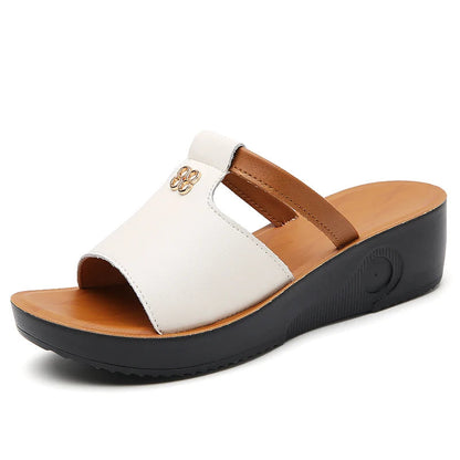 White and tan leather women's platform slide sandals with cutout sides, gold accent, and black wedge sole.