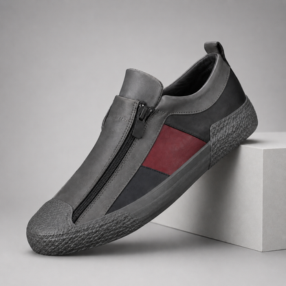 Gray leather slip-on sneakers with front zipper closure and red stripe accent on textured rubber sole