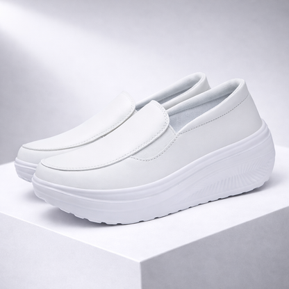 White women's slip-on platform sneakers with thick cushioned sole, smooth leather upper, and minimal stitching detail.