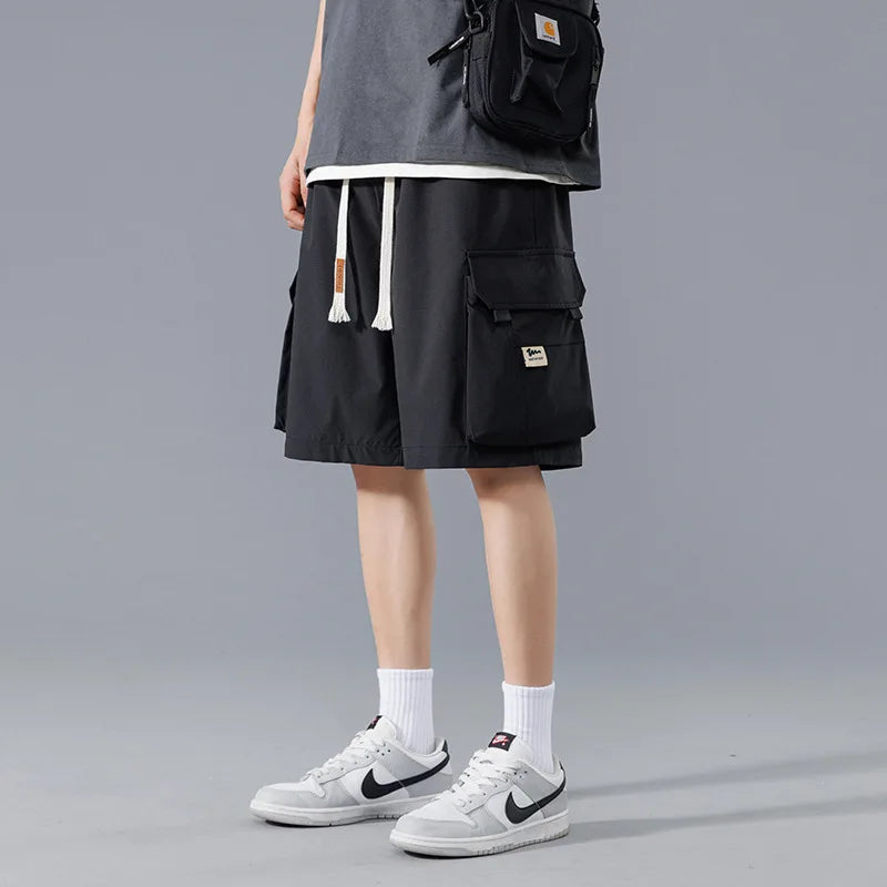 Men's black cargo shorts with white drawstring, side pockets, worn with Nike sneakers and a Carhartt crossbody bag