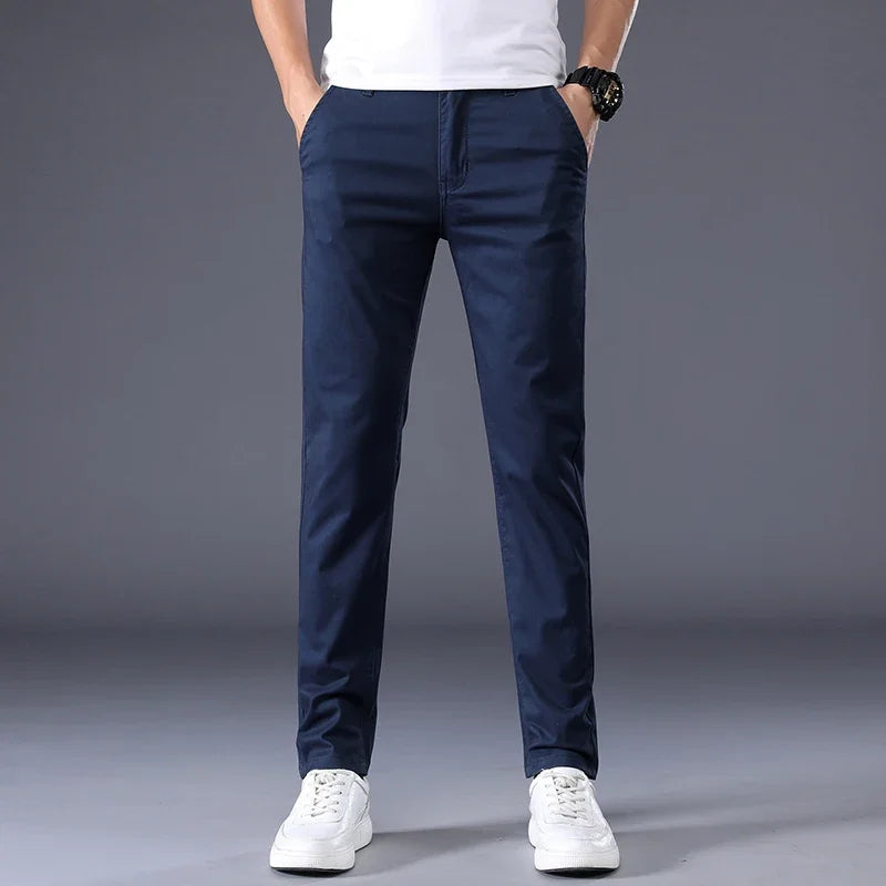 Man wearing slim fit navy blue cotton dress pants with white sneakers and white t-shirt, front view