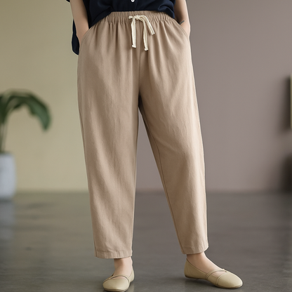 Women's khaki linen drawstring tapered pants with elastic waist, side pockets, paired with beige flats.