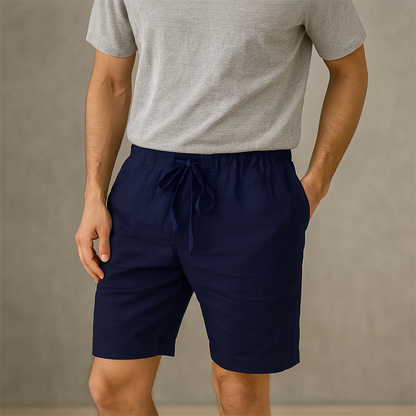 Man wearing navy blue linen drawstring shorts with elastic waistband, paired with a gray t-shirt, neutral background.