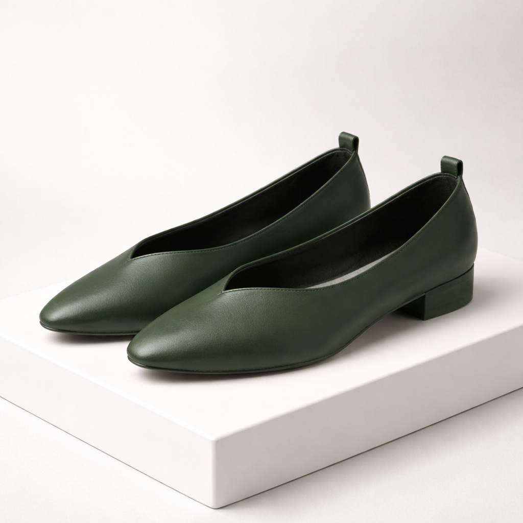 Dark green leather pointed-toe block heel pumps with V-cut vamp and pull tab, displayed on white platform