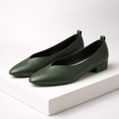 Dark green leather pointed-toe block heel pumps with V-cut vamp and pull tab, displayed on white platform